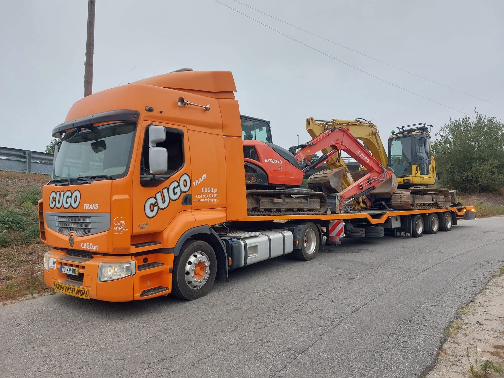 Camião laranja CUGO a transportar máquinas pesadas